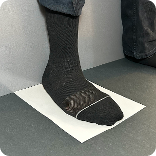 A sock-clad foot standing on the sheet of paper