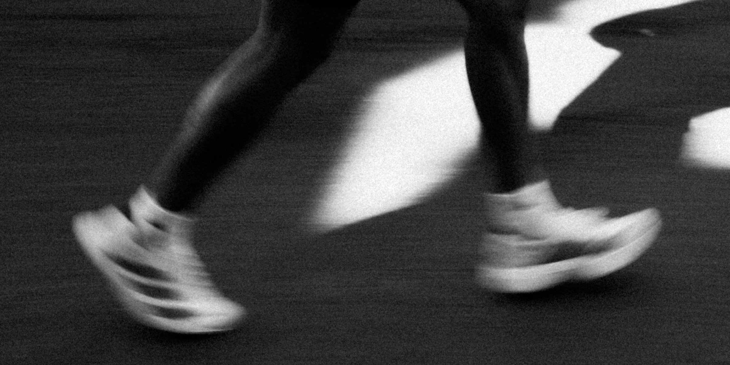 Runner mid-stride, motion-blurred black-and-white photograph